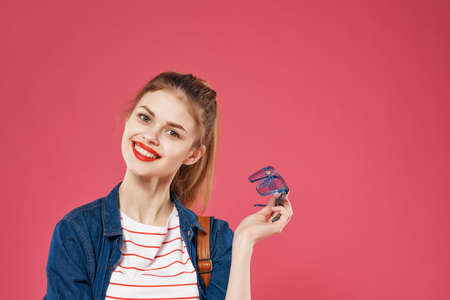 pretty young woman holding hair school backpack pink backgroundの写真素材