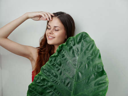 smiling woman with closed eyes green palm leaf exotic studio