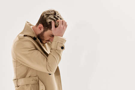 a man in a coat holds sleeves for the head fashionable hairstyle autumn style Copy Space