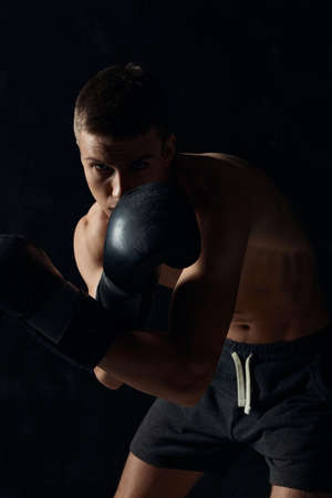 boxer in gloves on a black background bent down croppedの写真素材