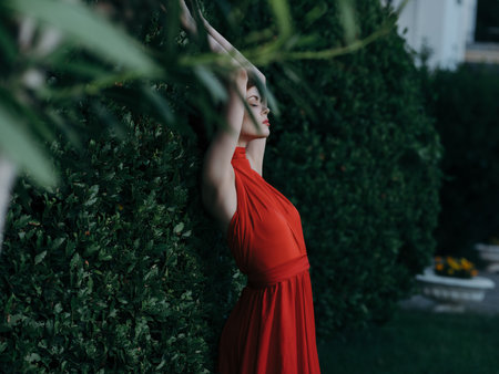 woman near bush in red dress and fairy garden decorationの写真素材