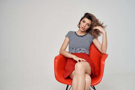 pretty woman sitting on chair fashion clothes light background