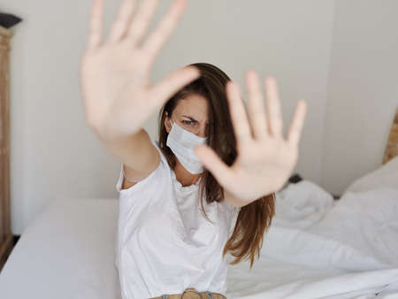woman in medical mask gesturing with her hands in an isolated room