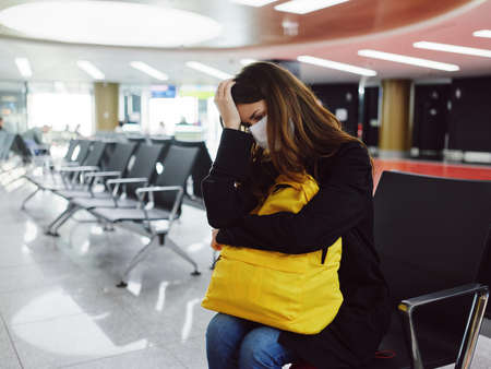 woman at the airport holding her head medical mask waitingの写真素材