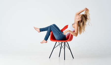 pretty woman on red chairs posing fashion entertainment light backgroundの写真素材