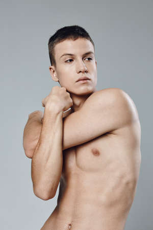 guy twisted his arms on a gray background torso muscles biceps bodybuilding Fitnessの写真素材