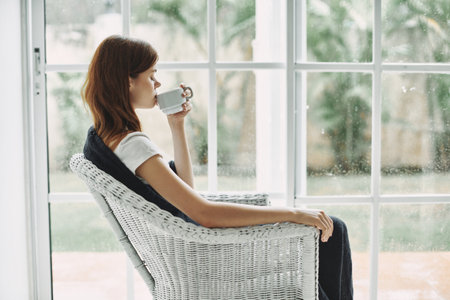 woman at home in armchair with cup of coffee stained glass window interiorの写真素材