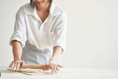 woman in chefs uniform baker rolling dough kitchen work