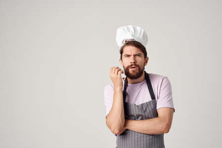 Cheerful chef in an apron industry work in a restaurant light backgroundの写真素材