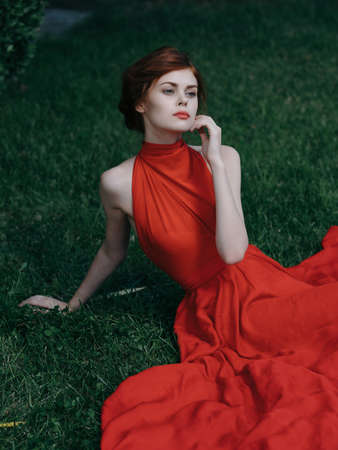 woman in red dress sitting on the lawn in the garden fantasy decorationの写真素材