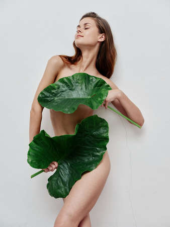 woman with green leaves cover body parts with closed eyesの写真素材