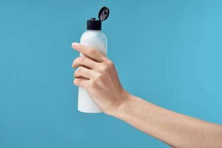 jar of cream in hand close-up skin care blue background cosmetics