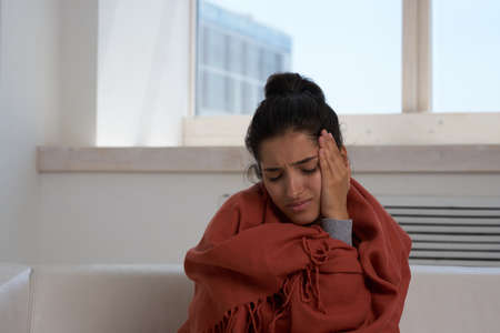 woman sitting at home feeling unwell health problems