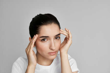 woman in white t-shirt holding face dissatisfaction problem isolated backgroundの写真素材