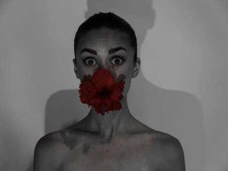 surprised woman with bare shoulders flower in mouth black and white photo