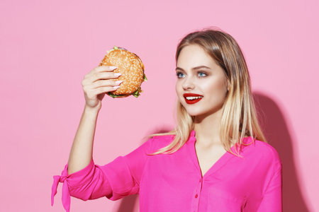pretty woman in pink shirt with hamburger fast food dietの写真素材