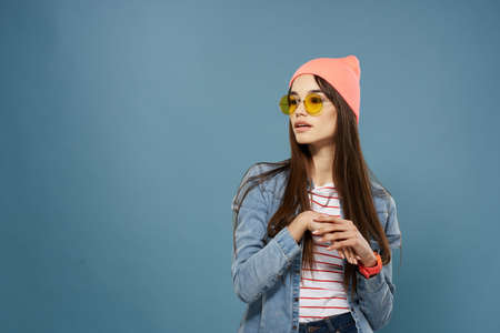 pretty woman wearing glasses modern clothing denim jacket blue backgroundの写真素材