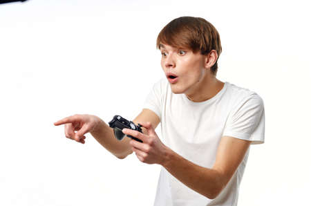 man in white t-shirt with joysticks in hands playing entertainment technologyの写真素材