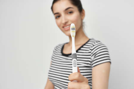cheerful woman brushing teeth hygiene light backgroundの写真素材