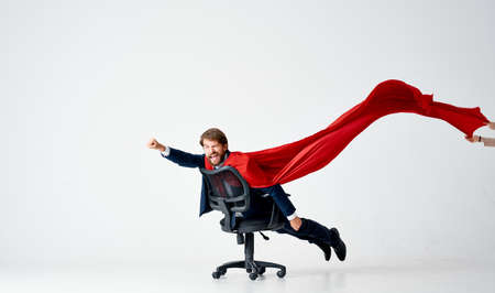 a man with a red raincoat rolls around in an office chair manager superheroの写真素材