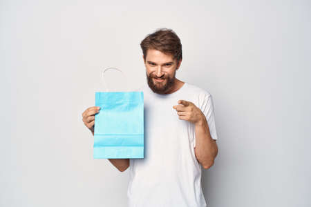 man in white t-shirt blue package shopping light background