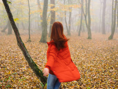 woman in red jacket in autumn forest fog nature fresh airの写真素材