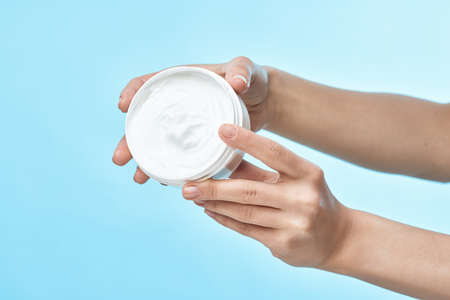 jar of cream in hand skin care close-up cosmetics blue backgroundの写真素材