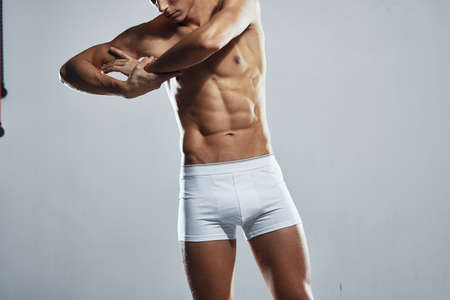 sporty man with pumped up muscular body in white shorts workout light backgroundの写真素材