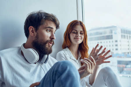 boy and girl sit near the window with headphones together apartmentsの写真素材