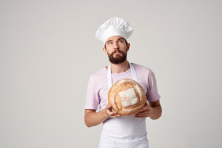 bearded man in a white apron with bread in the hands of a bakerの写真素材