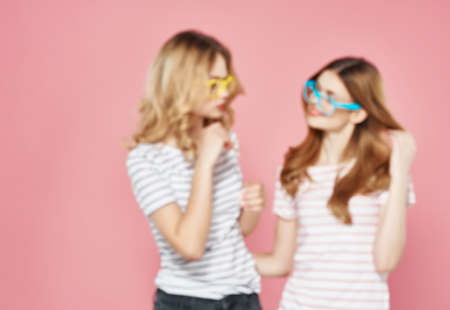 two cheerful girls are standing next to each other hugs fashion summer pink backgroundの写真素材
