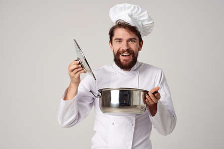 Cheerful male chef looking into the pan preparing food gourmetの写真素材