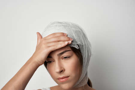 woman holding onto bandaged head injury health problems treatmentの写真素材