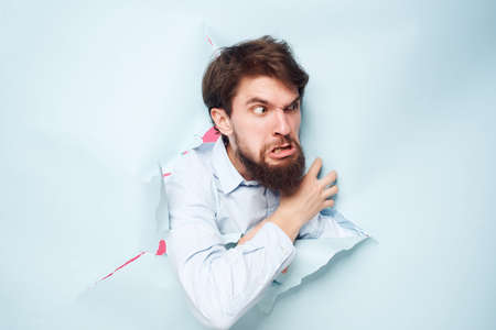 bearded man breaks through the background fun isolated backgroundの写真素材