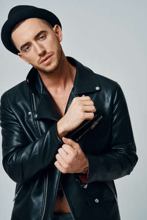 man in black leather jacket hat posing fashion confident light background