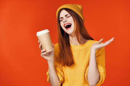 pretty woman in yellow hat with a cup of hot drink in hands emotions isolated background