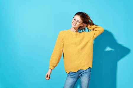 red-haired woman in yellow sweater holding hair fashion blue background
