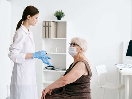doctor next to an elderly woman patient hospital vaccination immunity protectionの写真素材