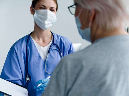 elderly woman in medical mask communicates with nurse in hospital and stethoscope covid passport