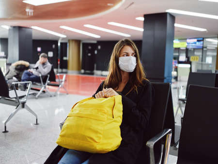 woman passenger yellow backpack airport waiting medical maskの写真素材
