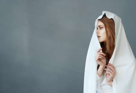 pretty red-haired woman covers her head with white clothの写真素材