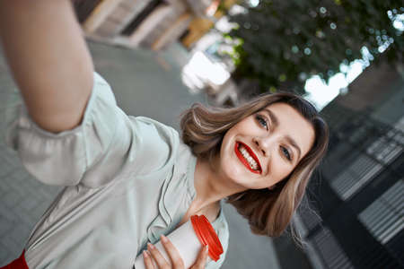 cheerful blonde with a cup of coffee on the street lifestyleの写真素材