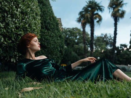 attractive woman in green dress lies on the grass decorationの写真素材