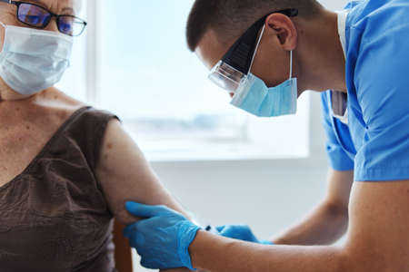 Male doctor giving an injection covid-19 passport patient treatmentの写真素材