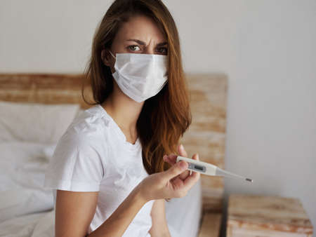 woman wearing medical mask thermometer health check dissatisfied facial expressionの写真素材