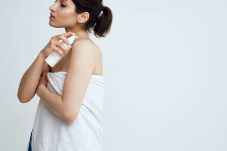 woman in towel applies lotion to bare shoulders clean skinの写真素材