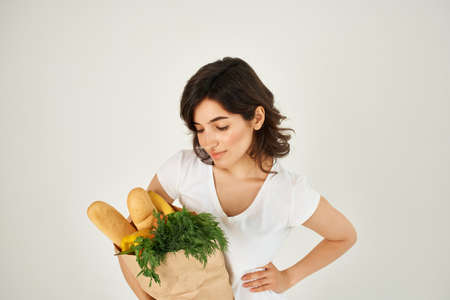 Woman in white t-shirt package with groceries in supermarket food deliveryの写真素材