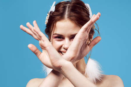 attractive woman naked shoulders fluffy earrings cosmetics blue backgroundの写真素材