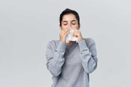 woman wiping her nose with a handkerchief health problems allergy infectionの写真素材