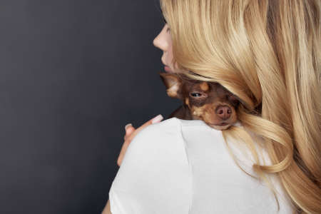 blonde girl holding a small purebred dog studio fashion